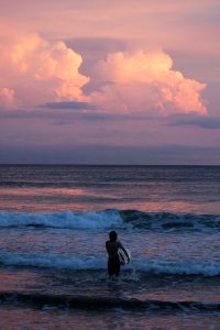 Person Carrying Surfboard Walking Against Sea Waves During Golden Hour photo