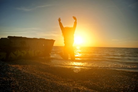 Person Jumping On Seashore During Golden Hour photo