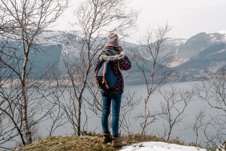 Woman In Brown Coat And Blue Jeans Near The Lake
