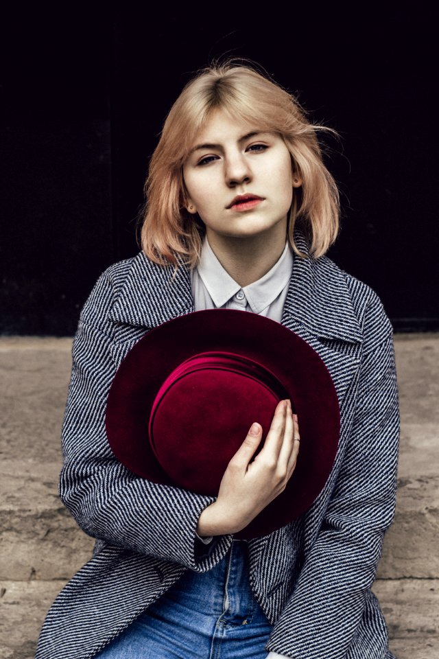 Woman In White Collared Top And Gray Coat Holding Red Fedora