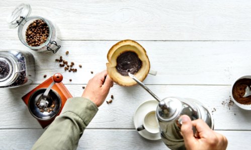 Person Pouring Hot Water In Mug With Ground Coffee photo