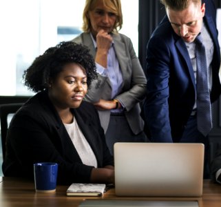 Woman Sitting In Front Of Table Beside Man Leaning On Laptop photo