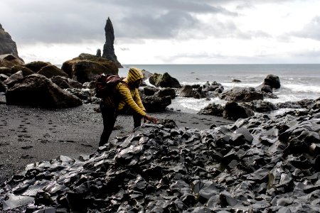 Person Wearing Hoodie Touching Stone In Seashore
