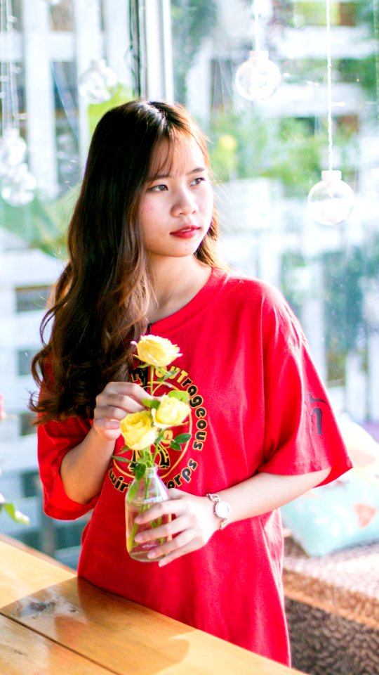 Woman Wearing Pink Scoop-neck Shirt While Holding Yellow Flowers photo