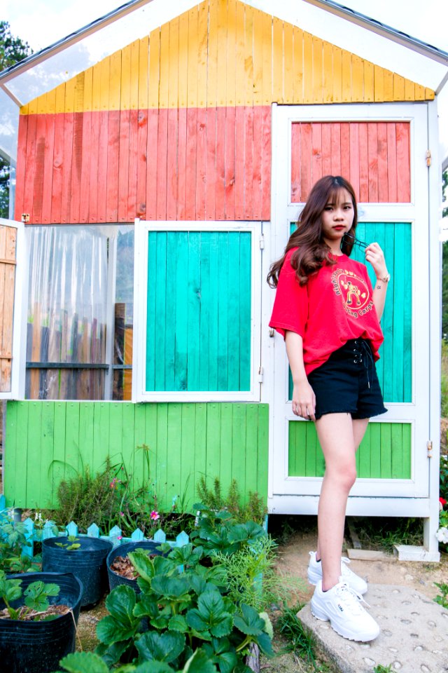 Woman Stands Near Multicolored Wooden House