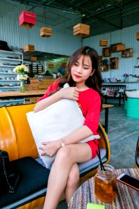 Smiling Woman Wearing Red Lipstick And Red Shirt Holding White Throw Pillow photo