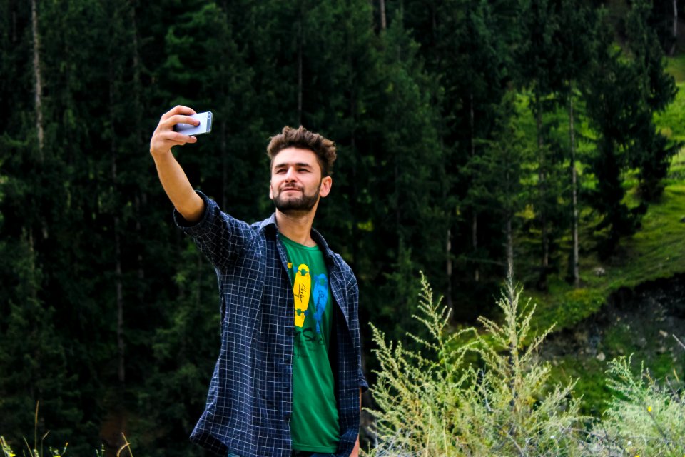 Man In Blue Sports Shirt And Green Top Taking A Selfie Near Green Trees