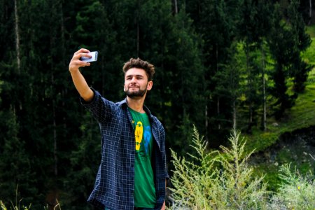 Man In Blue Sports Shirt And Green Top Taking A Selfie Near Green Trees