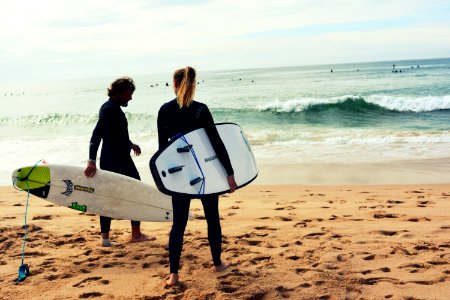 Man And Woman Holding Surfboards On Seashore
