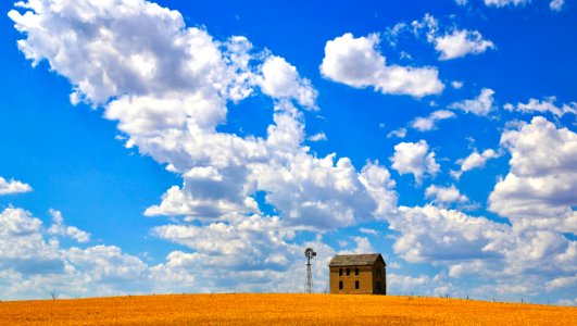 Brown Concrete House Near Tower Under Cloudy Sky