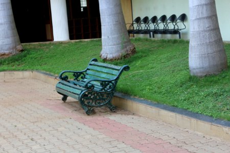 Green Metal Bench Beside Concrete Curb And Green Grass photo