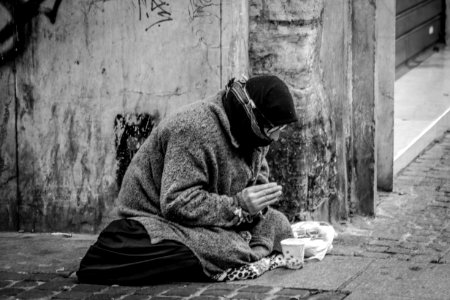 Grayscale Photography Of Man Praying On Sidewalk With Food In Front photo