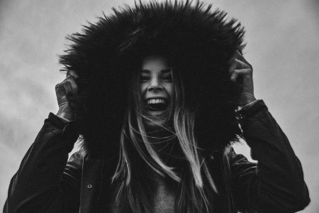 Grayscale Photo Of Laughing Woman Holding Her Hat photo