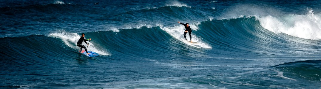 Two Surfers Gliding On Body Of Water