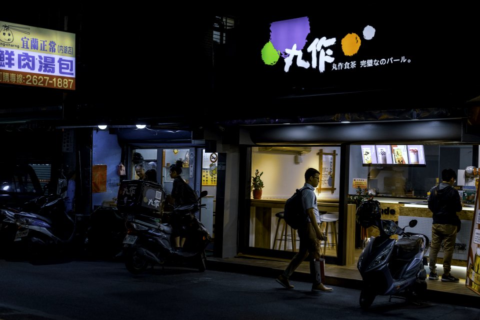 Man Standing Near White Motor Scooter At Night