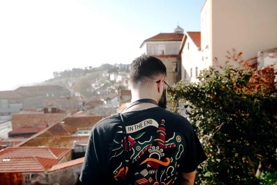 Man Wearing Black T-shirt Standing Near White Concrete Houses