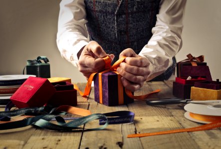 Person Tying Ribbon On Purple Gift Box photo