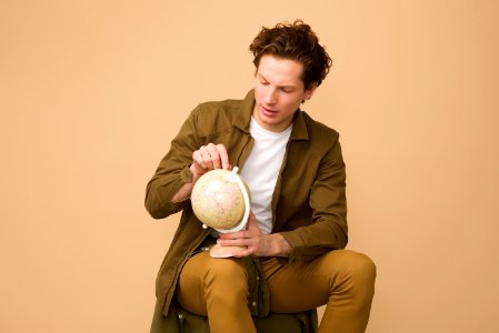 Man Sitting Holding White Desk Globe photo
