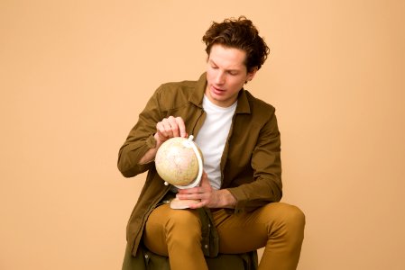 Man Sitting Holding White Desk Globe