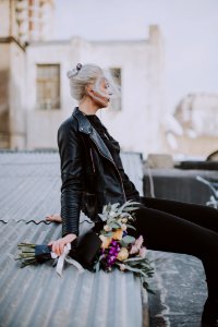 Woman Wearing Black Leather Full-zip Jacket Sitting On Galvanized Roof photo