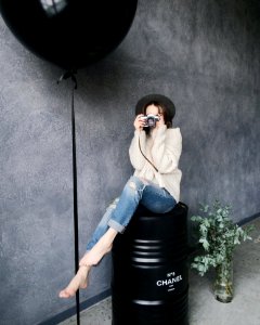 Woman Using Silver Camera Sitting On Black Container Drum photo