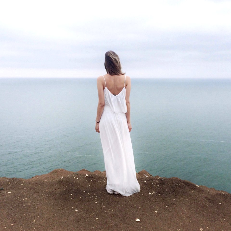 Woman In White Spaghetti Strap Dress Standing On Cliff
