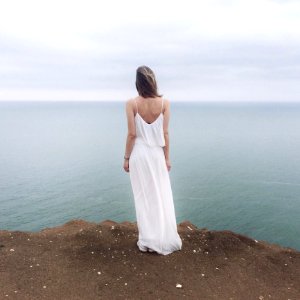 Woman In White Spaghetti Strap Dress Standing On Cliff photo