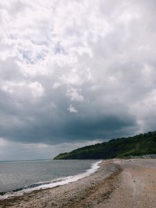 Beach Sand Near Body Of Water And Green Mountain Under Cloudy Sky photo