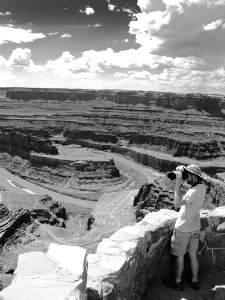 Man Standing Holding Camera Near Grand Canyon Grayscale Photo photo