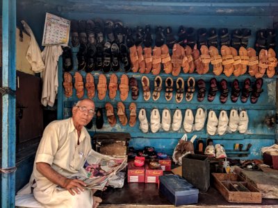 Man Reading Newspaper Surrounded By Shoes