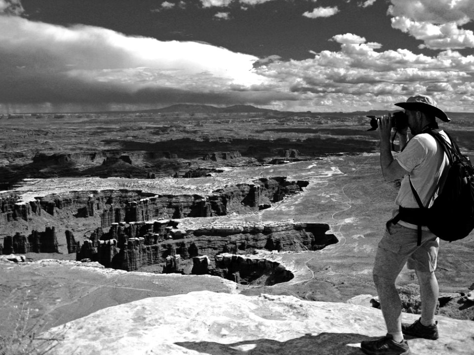 Grayscale Photo Of Man Taking Photo Of Canyons