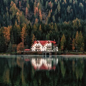 White And Orange House Beside Forest And Body Of Water photo