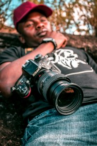 Selective Focus Black Nikon Dslr Camera With Zoom Lens On Lap Photo
