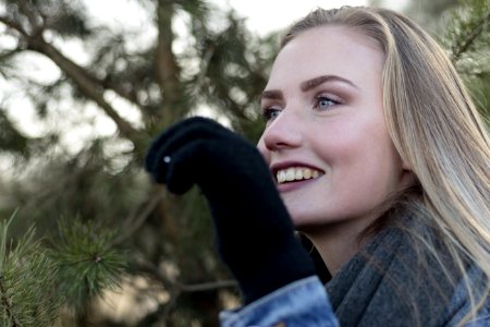 Woman Wearing Grey Scarf Holding A Pine Leaf While Smiling photo