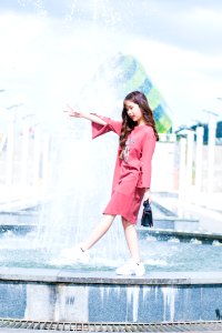 Woman Wearing Pink Long-sleeved Dress Walking On Fountain During Daytinme photo