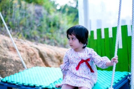 Girl Wearing White Long-sleeved Dress While Sitting On Swing photo