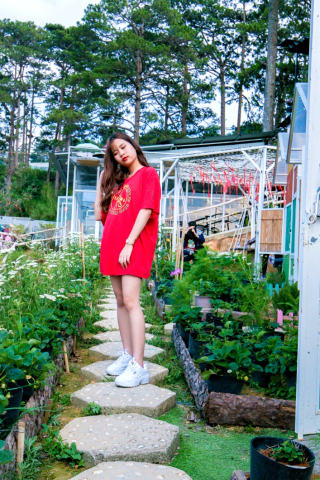 Woman Wearing Red Crew-neck Shirt Standing Between Plants Near Trees