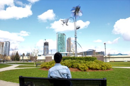 Man Wearing Blue Top Sitting On Black Bench