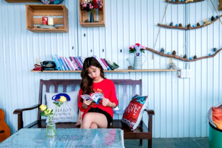 Woman In Red Shirt Reading Book While Sitting On Bench photo