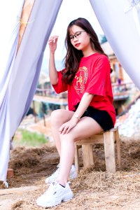 Woman Wearing Red Crew-neck Elbow-sleeved Shirt Sitting On Brown Wooden Stool photo