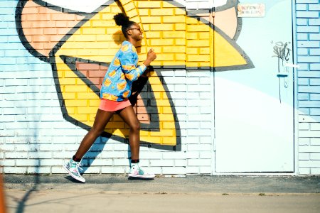 Woman Wearing Blue And Yellow Long-sleeved Shirt Walking Near White And Yellow Painted Wall photo