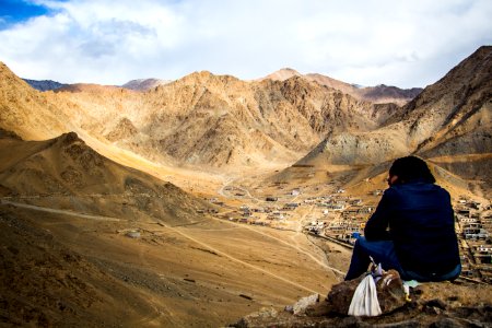 Person Sitting On Mountain Under White Sky photo
