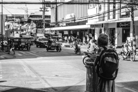 Person Wearing A Backpack In The Middle Of The Street In Grayscale Photo photo