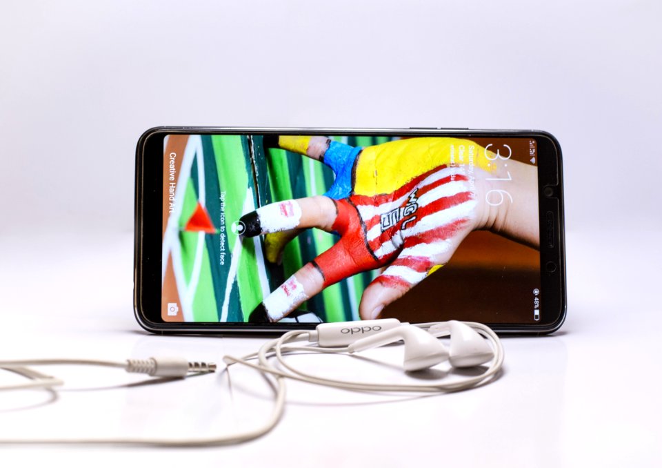 Black Android Smartphone Beside White Earphones