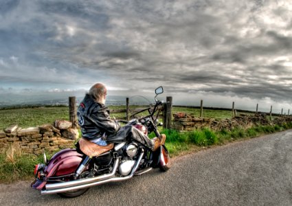 Man Wearing Black Leather Jacket Riding Cruiser Motorcycle On Road photo