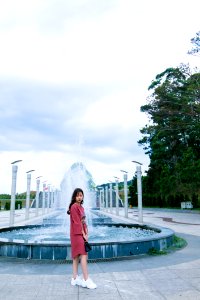 Woman In Red Long-sleeved Dress Standing Near Water Fountain At Daytime photo