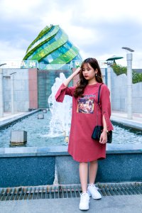 Woman Wearing Maroon Crew-neck Long-sleeved Dress Standing Next To Fountain Under Cloudy Sky