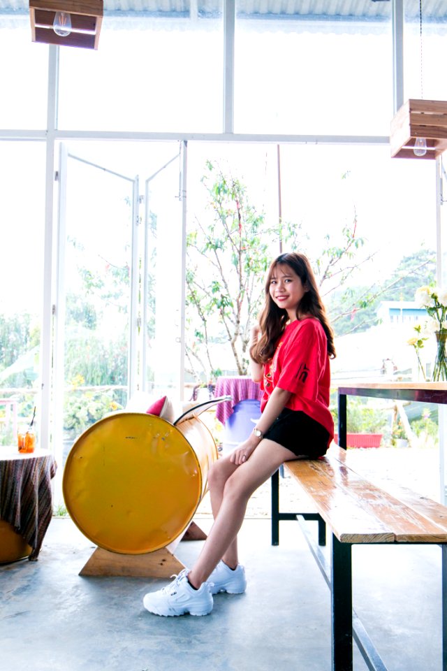 Woman Wearing Red Blouse And Black Short While Sitting On Table