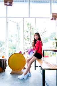 Woman Wearing Red Blouse And Black Short While Sitting On Table photo