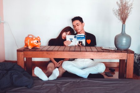 Couple Reading Book Sitting On Front Of Rectangular Brown Wooden Coffee Table